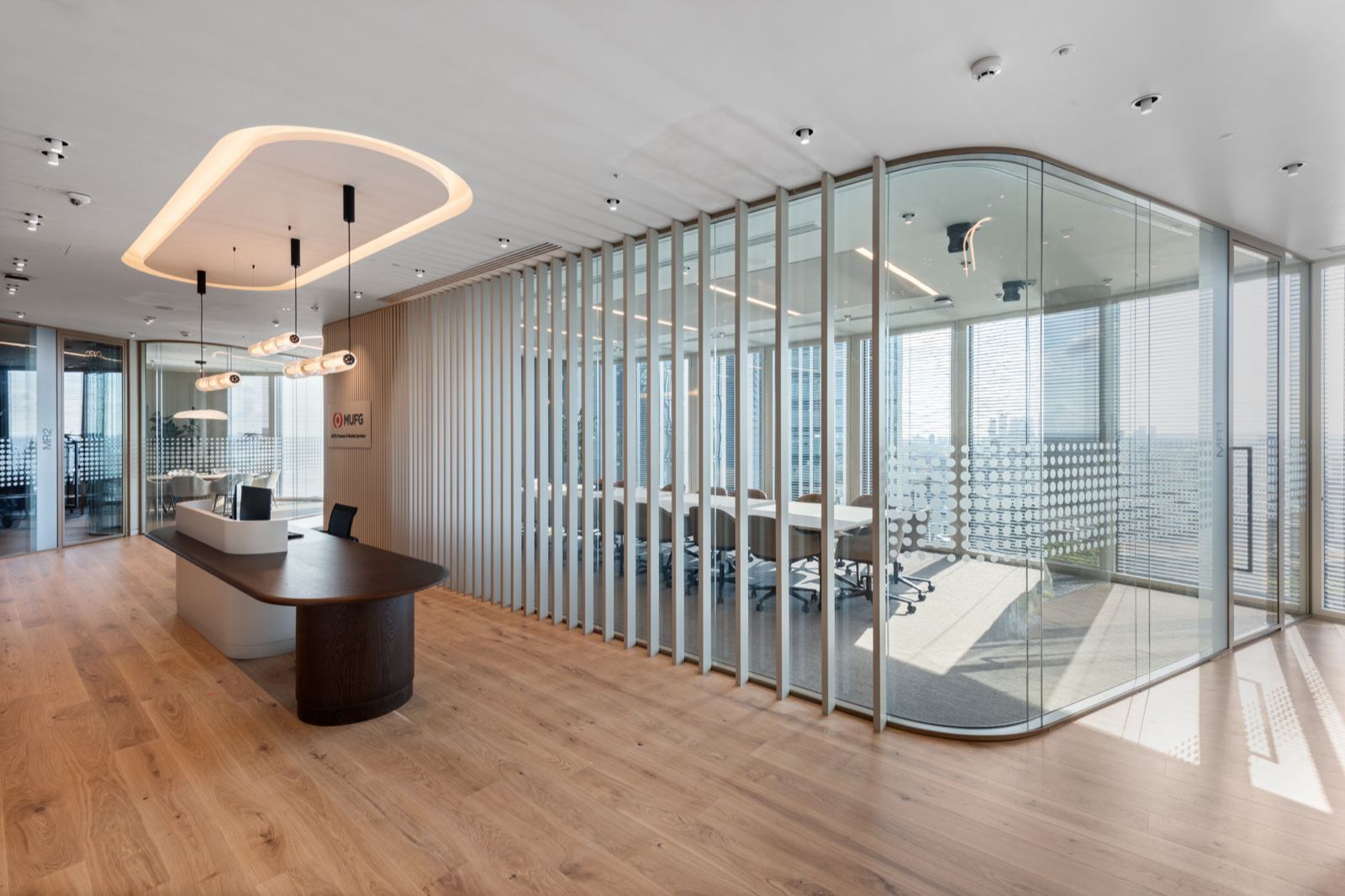 Curved glazed meeting room within an open workplace.